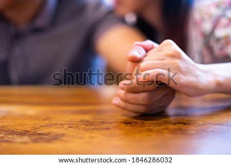 Closeup on two young lovers holding hands at a table, symbol sign sincere feelings, compassion, loved one, say sorry. Reliable person, trusted friend, true friendship concept. Selective focus.