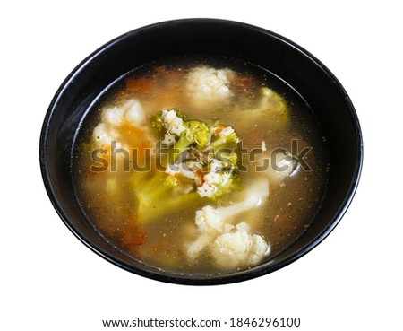 soup with stelline (italian pasta) and vegetables (cauliflower, broccoli, etc) in black bowl isolated on white background