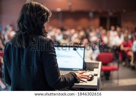 Female speaker giving a talk on corporate business conference. Unrecognizable people in audience at conference hall. Business and Entrepreneurship event. Royalty-Free Stock Photo #1846302616