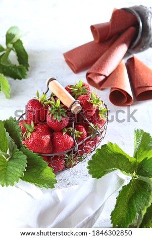 Strawberries in a wicker metal basket and strawberry marshmallows on a poor background. View from above. Copy space. Healthy food concept. Vertical photo.