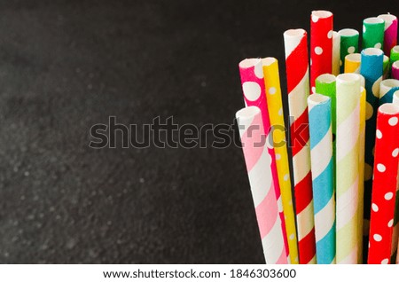 Colorful paper straws of different colors for cocktails and drinks on dark background.