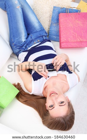 Young woman sitting with  on sofa and holding credit card in her hand, at home