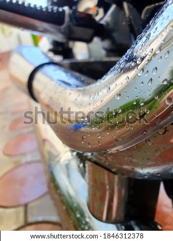Big chromed exhaust pipe with water drips on motorcycle. Side wiev