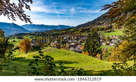 The autumn view over a small village to the Valley of Rhine and the Swiss mountains. the colorful trees and the yellow-green meadows makes a happy exhilarating impression. Feldkirch, Vorarlberg Royalty-Free Stock Photo #1846312819