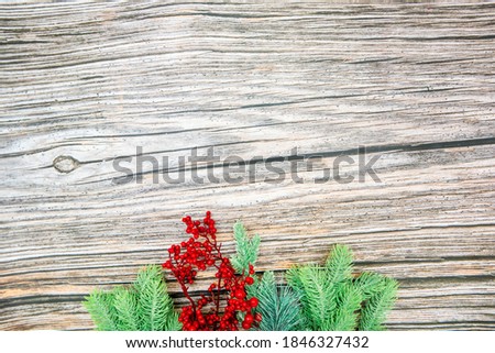 spruce branch with berries spruce branches and red beads on a string scattered on a wooden background from below top view with space for text or inscription