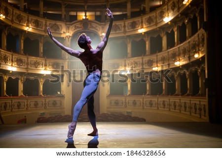 Cinematic shot of an young athletic classical ballet male dancer is performing a choreography on a classic theatre stage with dramatic lighting before start of a show. Royalty-Free Stock Photo #1846328656