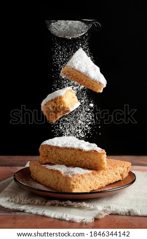 Delicious freshly baked sponge cake whit two piece of cake falling and sprinkling icing sugar Royalty-Free Stock Photo #1846344142