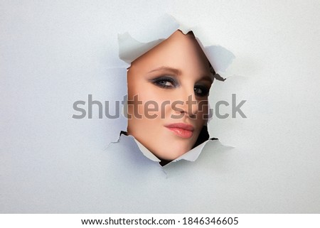 girl with makeup looks through a hole in the sheet, abstraction, background. High quality photo