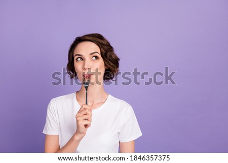 Portrait photo of dreamy girl licking fork thinking about diet looking at empty space isolated on bright purple color background Royalty-Free Stock Photo #1846357375