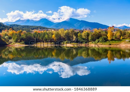 Bansko, Bulgaria autumn panorama background of Pirin mountain peaks, lake water, colorful green, red and yellow trees reflection Royalty-Free Stock Photo #1846368889