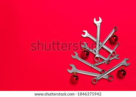 Christmas tree made of wrenches decorated with balls on a red background. New Year banner with tools. Postcard with place for greeting text for happy new year with industrial holiday concept. Close-up Royalty-Free Stock Photo #1846375942