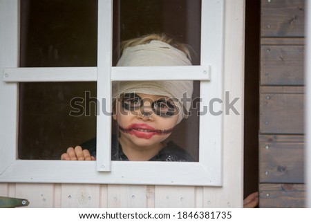Scary toddler child in halloween costume, playing with carved pumpkins and candles
