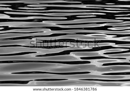 black and white water texture. background .Reflections of the sun in the small waves, the reflections form peculiar white lines and patches in the restless black water