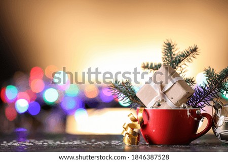 Cup with Christmas decor on table against blurred lights