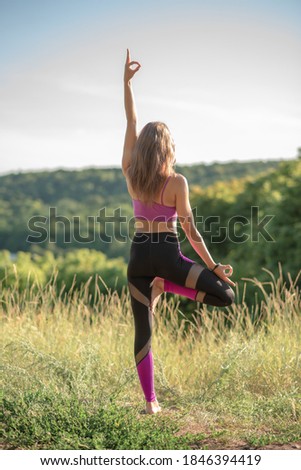 A slender girl does yoga in nature on a sunny day