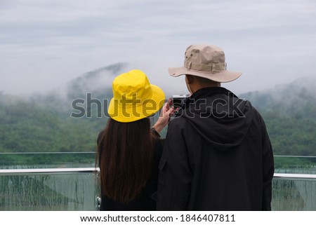 two people on the skywalk taking a photo against fog mountain background