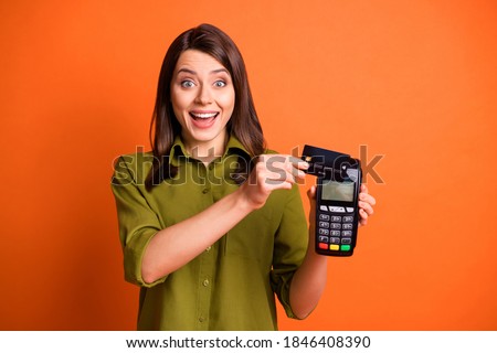 Photo portrait of young girl paying with plastic card terminal laughing isolated on vibrant orange color background