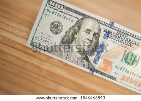 100 Dollars bill and portrait Benjamin Franklin on USA money banknote. Hundred dollar bills on wooden background.
