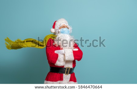 Merry Christmas and Happy Holidays! Santa Claus in face mask on bright color background. Covid-2019