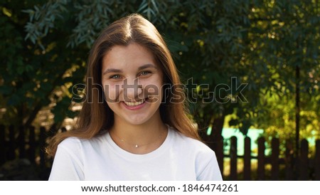 Young beautiful caucasian girl looking at the camera, embarrassed and smiling. Street portrait of a teenager. Calm emotion. Royalty-Free Stock Photo #1846474261
