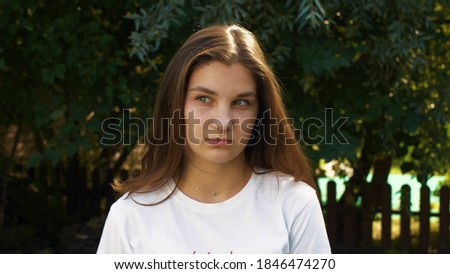 Young beautiful caucasian girl is sad tilting her head to the side. Street portrait of a teenager. Calm emotions, mobile facial expressions. Royalty-Free Stock Photo #1846474270