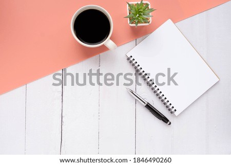 Top view of open school notebook with blank pages and pencil with coffee cup on pink and white two-tone background. Flat lay, creative workspace office. Business or education concept with copy space.