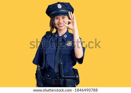 Young beautiful girl wearing police uniform smiling positive doing ok sign with hand and fingers. successful expression. 