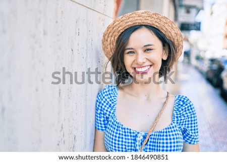 Young beautiful girl smiling happy leaning on the wall at street of city