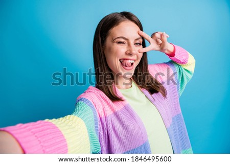 Portrait of beautiful brown haired girl take selfie make v-sign wink flirty isolated on shine blue color background
