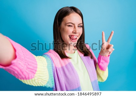 Photo of beautiful flirty young woman take selfie make v-sign wink good mood isolated on blue color background
