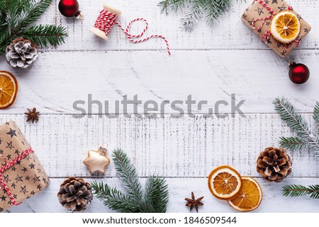 Сhristmas background with fir branches, pinecones, gift box, dried oranges, star anise and berries on the old  white wooden board. Top view.