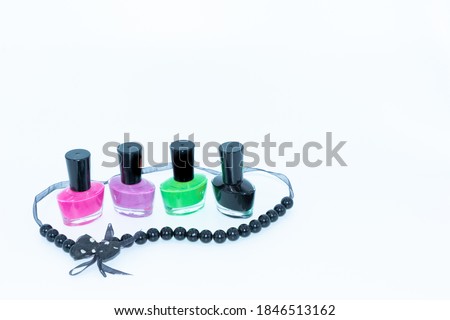 Selective focus image of Nail polish bottles of different colors and a beautiful necklace around it with white background