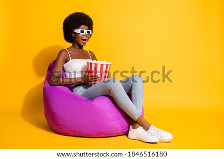 Photo of funny excited young woman wear casual clothes 3d eyewear sitting bean bag holding popcorn box isolated yellow color background