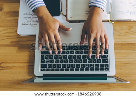 Topview flat lay of business working place with laptop, phone and woman hands typing.
