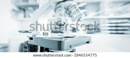 Science microscope on lab bench. Microbiology laboratory. Blue toned image of binocular microscope Royalty-Free Stock Photo #1846554775