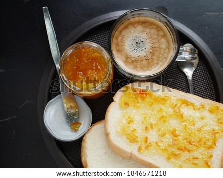 Hot coffee with thick, soft bread spread with orange jam. Quick menu for breakfast