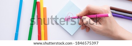 female hand writing with felt-tip pen over paper note on table, close view. High quality photo