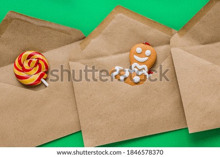 The brown envelopes contain a gingerbread man and a lollipop as a gift for Christmas and New Year. Flat lay. View from above.