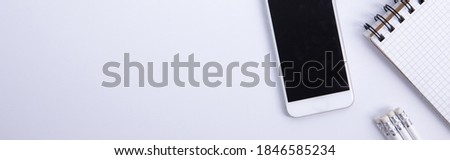 new modern smartphone with pencils and notebook isolated on white background, close view . High quality photo