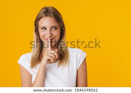 Happy beautiful girl smiling and showing silence gesture isolated over yellow background