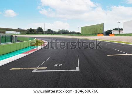 Motorsport background empty circuit asphalt track turn low angle view, cloudy blue sky and banner copy space