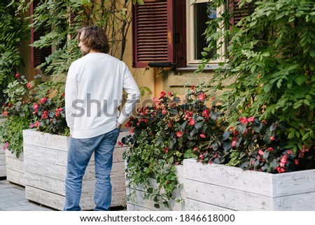 Man wearing white sweatshirt or hoodie for mock up, logo designs or design prints with with free space on the city streets.