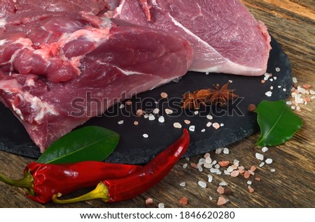 Fresh raw meat on old wooden board with spices. Boneless lamb steak meat
