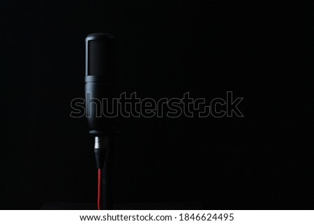 black condenser mic with red wire is only partially visible because there is a white color on one side