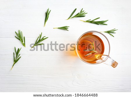 Herbal tea with rosemary in a glass cup on a white wooden background with place for text. Rosemary tea. Article, poster. Royalty-Free Stock Photo #1846664488