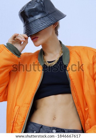 Model in fashion urban street outfit. Trendy orange bomber jacket and stylish bucket hat. Fall winter seasons lookbook. Style in details