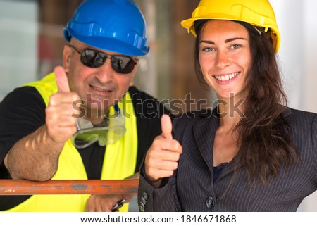 Positive emotions: enjoying the teamwork. Cheerful and smiling construction workers posing showing thumbs up gesture