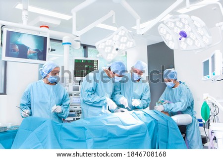 A medical team performing surgical operations while standing around some latest medical equipment and top end machinery in an operating suite Royalty-Free Stock Photo #1846708168