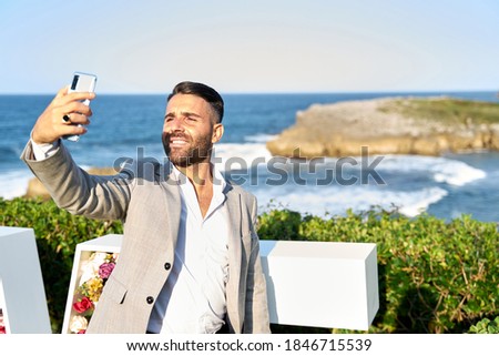Elegant young man taking selfie. In the background the sea of Asturias.