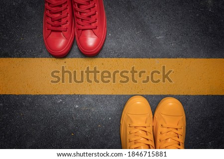 Social distancing concept - to avoid spreading of virus. Two people standing opposite each other divided by the yellow asphalt line, top view. Royalty-Free Stock Photo #1846715881